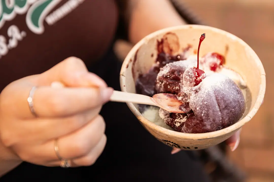 Colher pegando açaí com cobertura e cereja, de perto