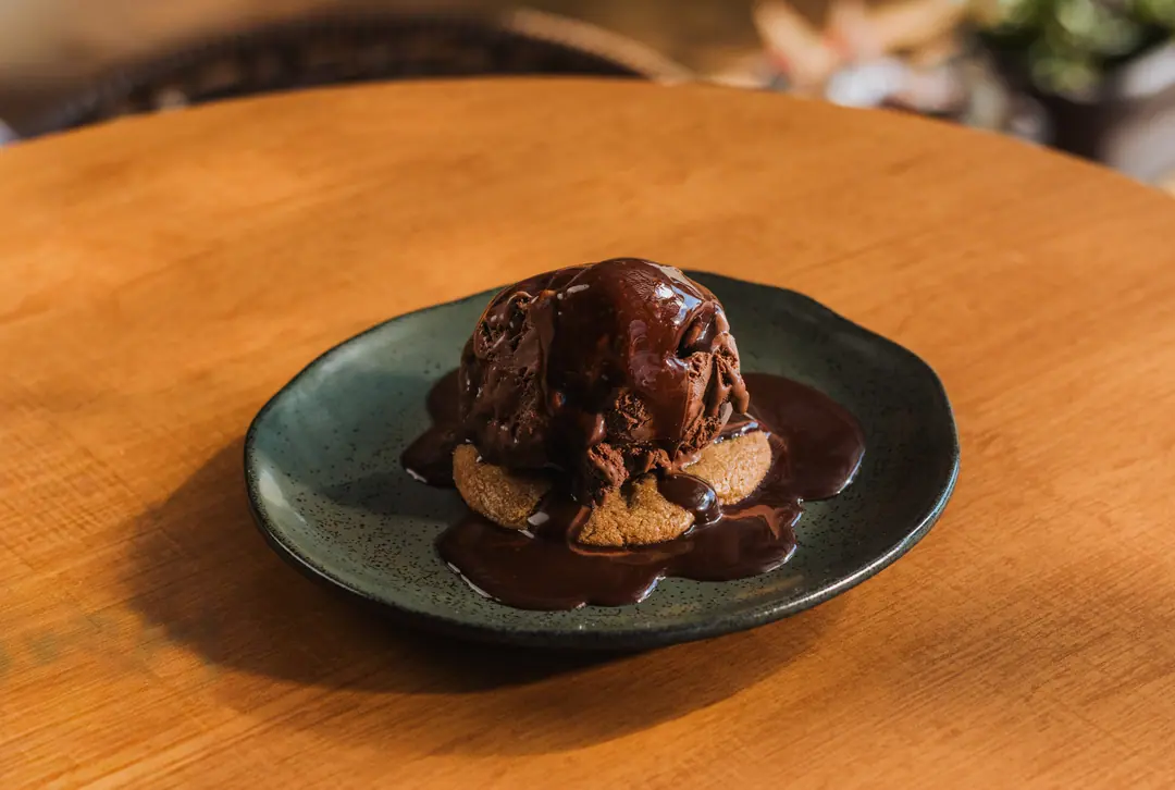 Cookie com sorvete e calda, visto de cima, na mesa de madeira